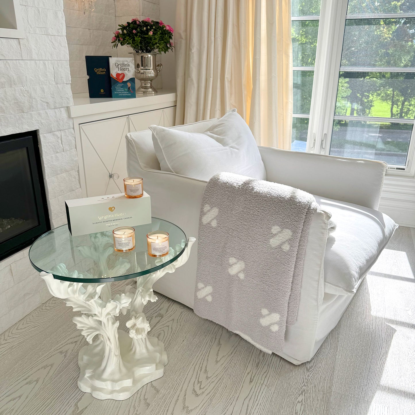 Griffin's Heart candles on a side table with the Griffin's Heart pet loss book in the background, Luxe throw over arm of chair, showing the complete healing companion product collection, SKU: GH002.